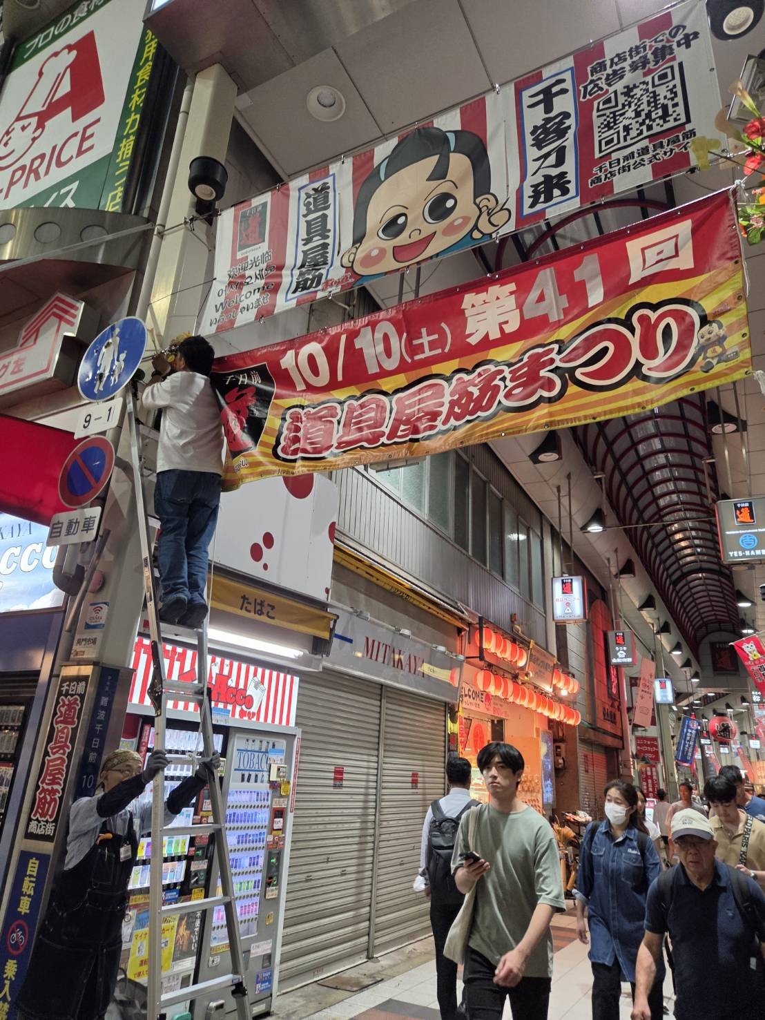 第41回道具屋筋まつりの横断幕をアーケードに設置する様子